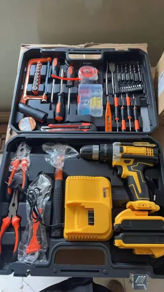 Cordless drill and hand tool kit open in its carry case, with drill, two batteries, charger, pliers, hammer and screwdrivers